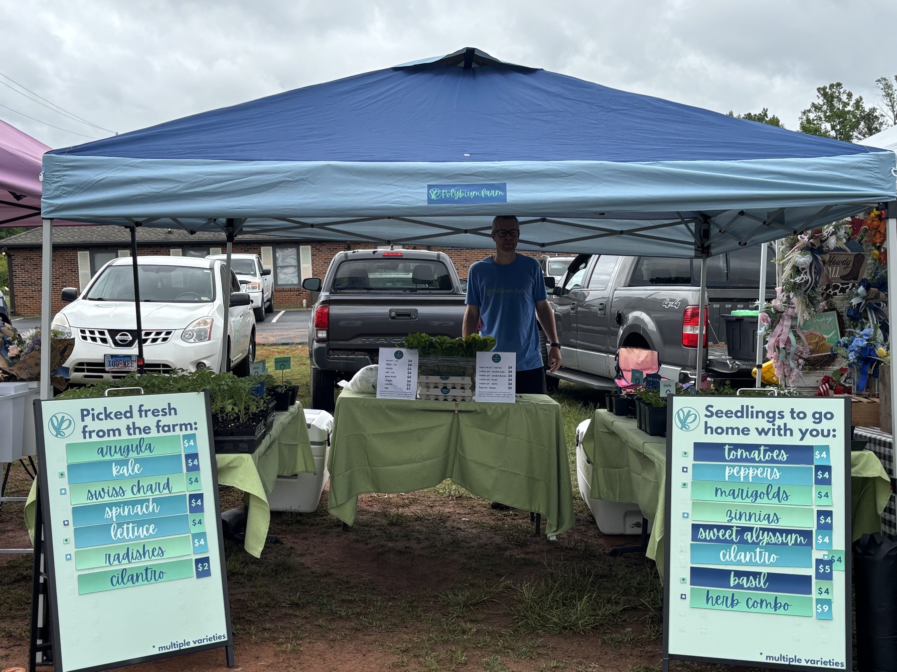 Polybium Farm market booth at Fluvanna Farmers Market with seedlings and fresh produce signage